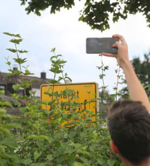 Handy nimmt Ortsschild auf und Fotowettbewerb